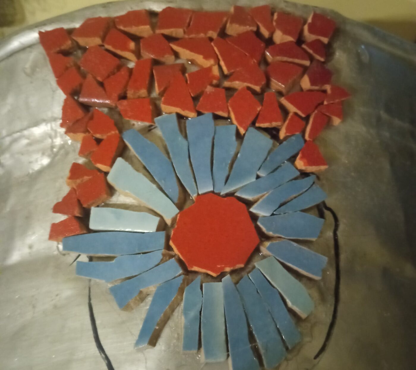 A mosaic being laid on a round form